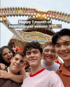 a group of young men standing next to each other in front of a merry go round