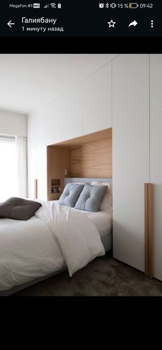 a bed with white sheets and pillows in a bedroom next to a wall mounted cabinet