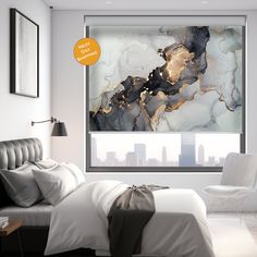 a white bed sitting under a window next to a wall mounted art piece in a bedroom