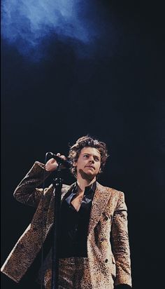 a man in a suit and tie holding a microphone up to his ear while standing on stage