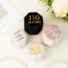 three personalized wedding rings on a table next to flowers and pearl necklaces,