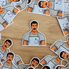 several stickers with the image of a man in aprons on them are arranged around a wooden table