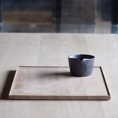 a small black bowl sitting on top of a wooden table next to a square object