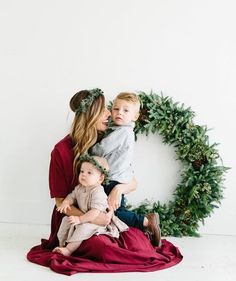 a woman and her two children are sitting in front of a wreath