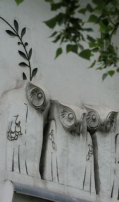 an artisticly designed sculpture on the side of a building with trees growing out of it