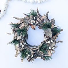 a wreath made out of driftwood and pine cones on a white background with beads