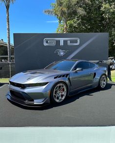 a silver sports car parked in front of a sign