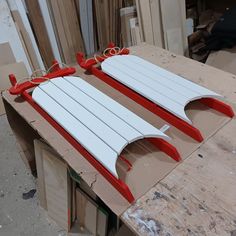 two red and white surfboards sitting on top of a wooden table