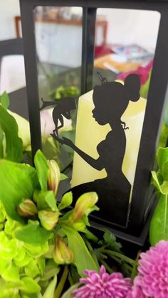 the silhouette of a woman holding a bird is shown in front of flowers and greenery