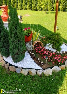 a garden with flowers and plants in the middle of it, surrounded by rocks and gravel