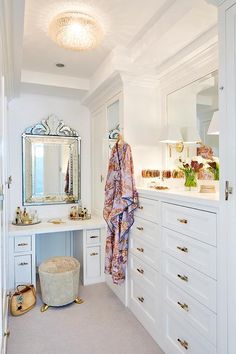 a dressing room with white cabinets and drawers