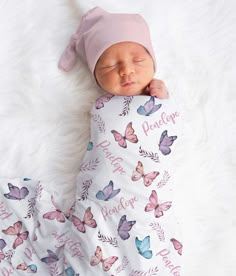 a baby is sleeping on a white blanket with pink and blue butterflies all over it