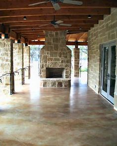 an empty patio with stone walls and ceiling fan in the center, surrounded by glass doors