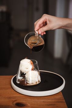 someone is pouring something into a small glass dish with ice cream and caramel on top