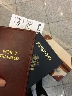 a person holding two passport cards in their hand, with the word world traveler written on them