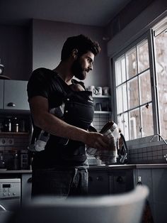 a man standing in a kitchen preparing food on top of a counter next to a window