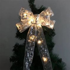 a lighted bow on top of a christmas tree