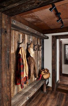 a wooden wall with coat hooks and coats hanging on it's sides in a hallway