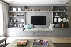 a living room filled with furniture and a flat screen tv on top of a wooden shelf