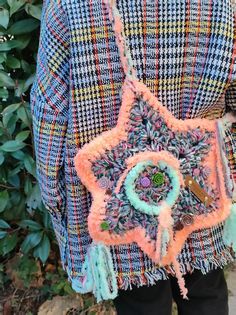 the back of a woman's jacket with an orange and blue bag hanging from it