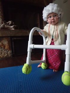 a small child wearing a santa hat and holding onto a white walker frame with tennis balls on it