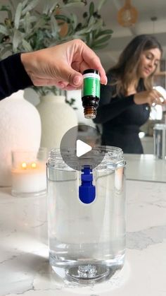 a person is pouring something into a glass container