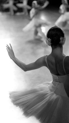 a black and white photo of a ballerina in the middle of a dance class