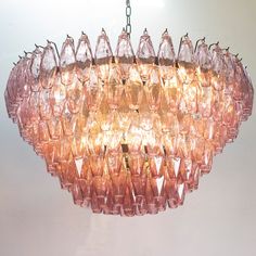 a pink chandelier hanging from a ceiling with glass pieces on it's sides