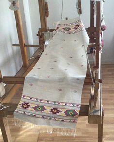 an old weaving machine with a white blanket on it's back and wooden frame