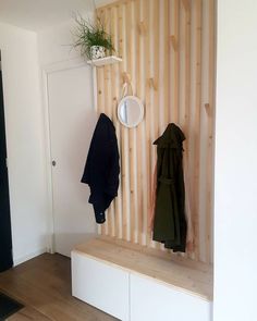 there is a coat rack with two coats hanging on the wall and a mirror above it