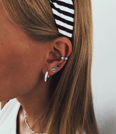 a woman wearing a pair of earrings and a striped headband is looking at the camera