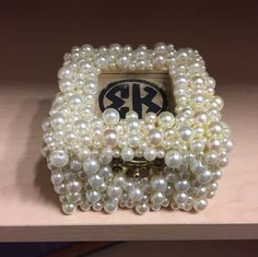 a bunch of pearls on a shelf with a monogram in the middle and an emblem