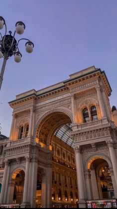 an ornate building with columns and arches under a street light at dusk in the city