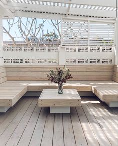 a wooden bench sitting on top of a wooden floor next to a vase with flowers