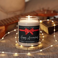 a candle with a red bow on it sitting next to a string of lights and a guitar