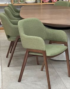 a wooden table with green chairs around it in a room filled with bookshelves