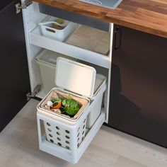 an open refrigerator with food in it on the floor next to a sink and counter