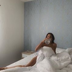 a woman laying in bed drinking water from a bottle