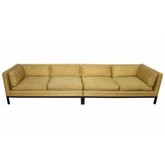 a beige leather couch with black legs and backrests on an isolated white background