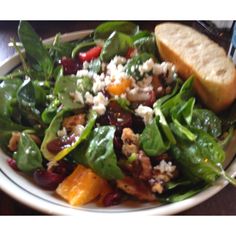 a salad with spinach, cheese and meat in a white bowl on a table