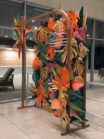 an artisticly designed sculpture in the lobby of a building that is decorated with tropical leaves