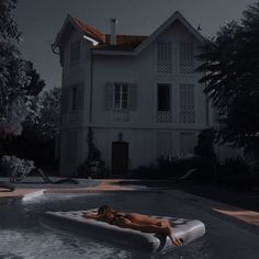 a woman laying on top of an inflatable mattress next to a large house