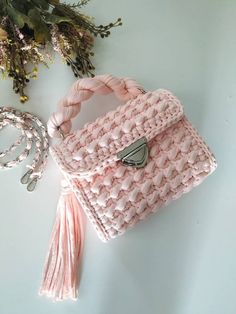 a pink purse sitting on top of a white table next to a flower pot and string