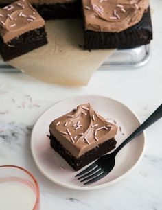 a piece of chocolate cake on a plate with a fork next to it and a slice missing