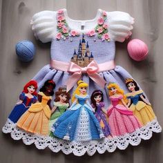 a crocheted dress with princesses on it and balls of yarn in the background