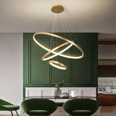 a modern chandelier hanging from the ceiling in a dining room with green chairs