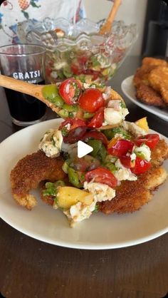 fried chicken with tomatoes, lettuce and other toppings on a white plate