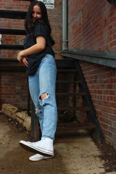 a woman leaning against a brick wall