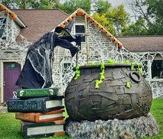 a halloween decoration in front of a house with books stacked on the ground next to it