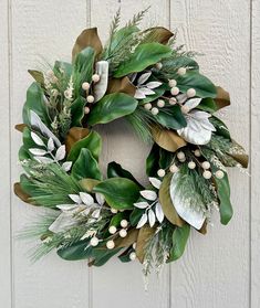 a wreath with green leaves and white berries